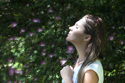 A Woman Standing Sideways, with Eyes Closed, and Head Tilted Up to Bask in the Sun