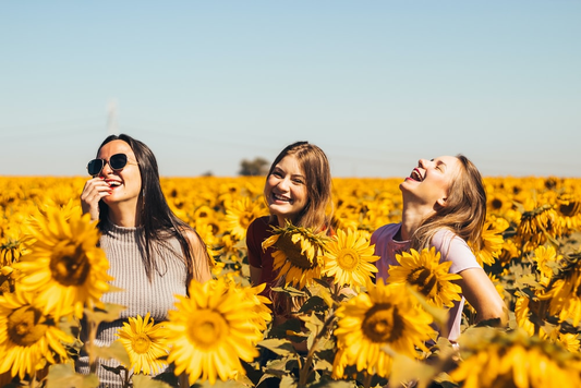 Three girls enjoying in a field of sunflowers