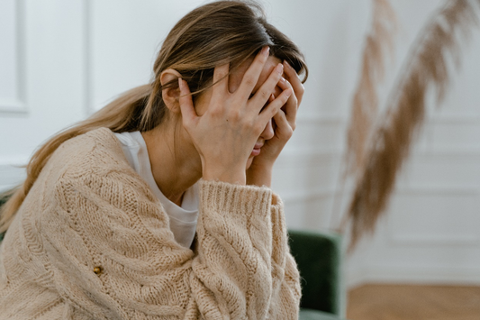 A woman sitting frustrated with her hands on her face.