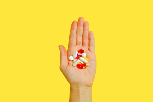 An open palm holding multiple vitamin supplements for consumption.